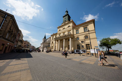 People in front of historic building against sky