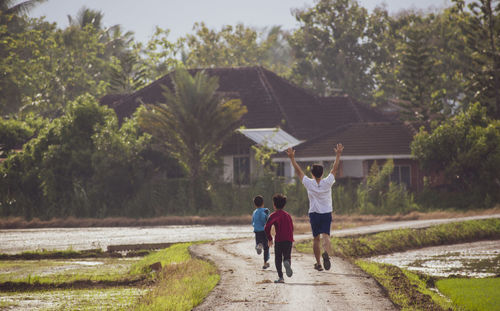 Rear view of people running on dirt road 