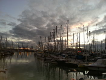 Boats in harbor against cloudy sky