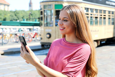 Beautiful young woman using mobile phone by train