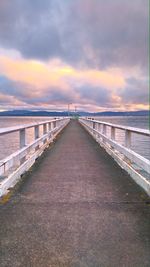 Footbridge over sea against sky during sunset