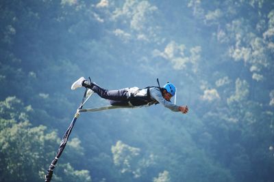 Low angle view of man paragliding against sky