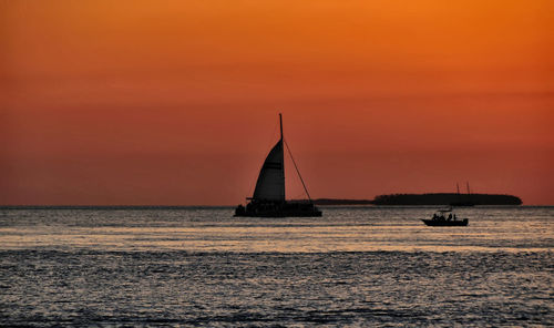 Boats on sea against orange sky