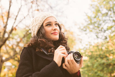 Portrait of smiling young woman holding plant during winter