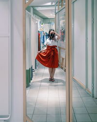 Full length of woman photographing while reflecting on mirror in store