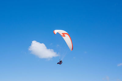 Low angle view of person paragliding against clear blue sky