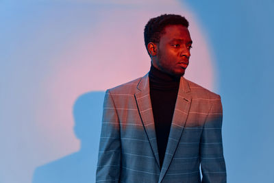 Young man wearing suit standing against wall