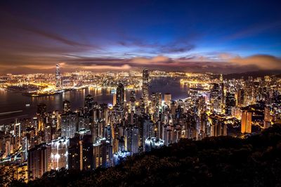 Illuminated skyscrapers at victoria harbour against sky