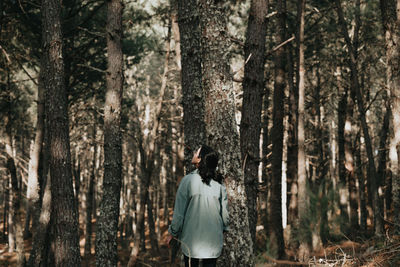 Rear view of woman standing in forest