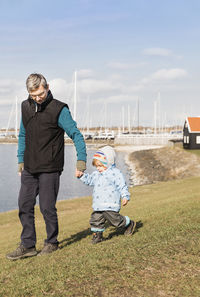 Full length of grandfather and grandson by sea