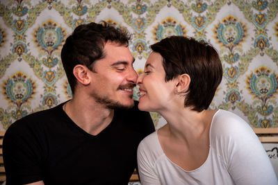 Young couple is sitting on the bed and kissing.