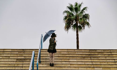 Woman standing on steps with umbrella