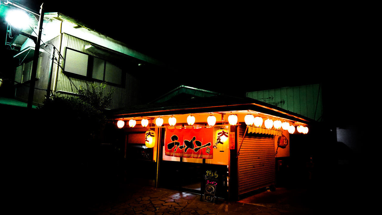 ILLUMINATED LANTERN BY BUILDING AT NIGHT