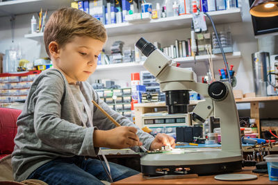 Side view of boy sitting on table