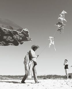 Low angle view of man standing on beach against clear sky