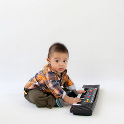 Boy playing guitar against white background