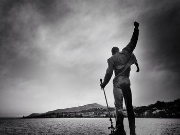 Human statue in lake geneva against cloudy sky