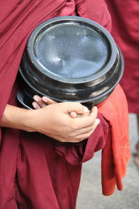 Midsection of monk holding container