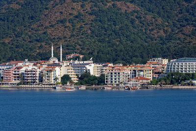 Buildings by sea against mountain