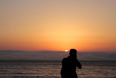 Silhouette man standing at beach during sunset