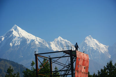 Low angle view of snowcapped mountains against clear blue sky