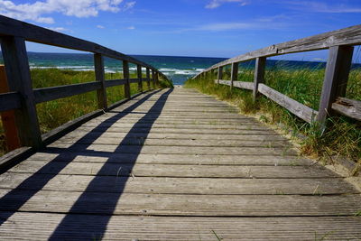 Wooden pier at beach against sky