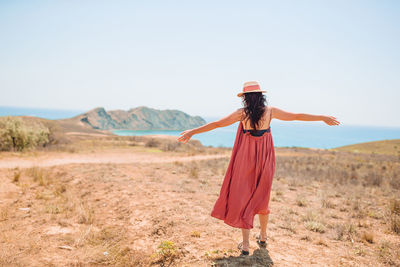 Rear view of woman standing on field against sky