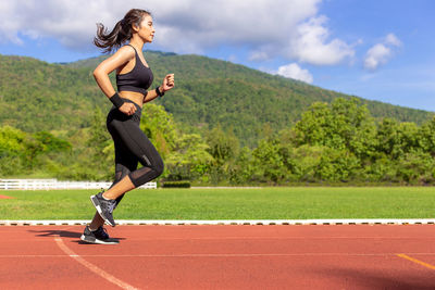 Side view of young woman running on road