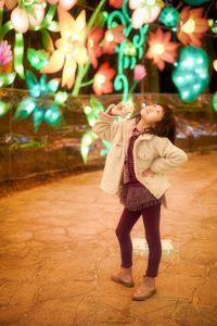 Full length of woman holding girl standing at night