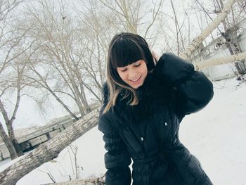 Woman in snow covered bare tree