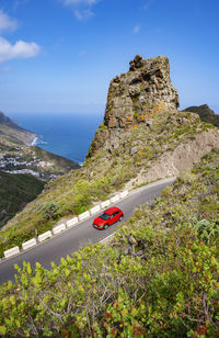 Car on road by sea against sky