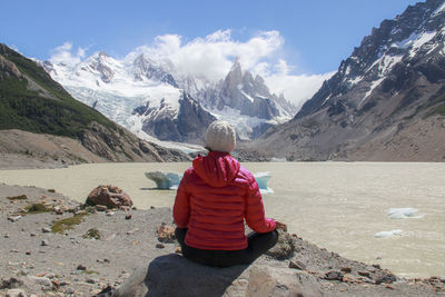 Rear view of woman meditating on mountain lake and glacier