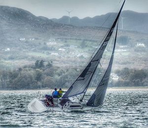 Sailboat sailing on sea against mountains