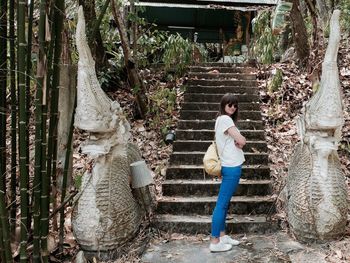 Full length of beautiful woman standing by steps at buddhist temple