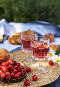 Picnic outdoors in lavender fields. rose wine in a glass, cherries and straw hat on blanket