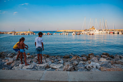 Rear view of people on sea shore against sky