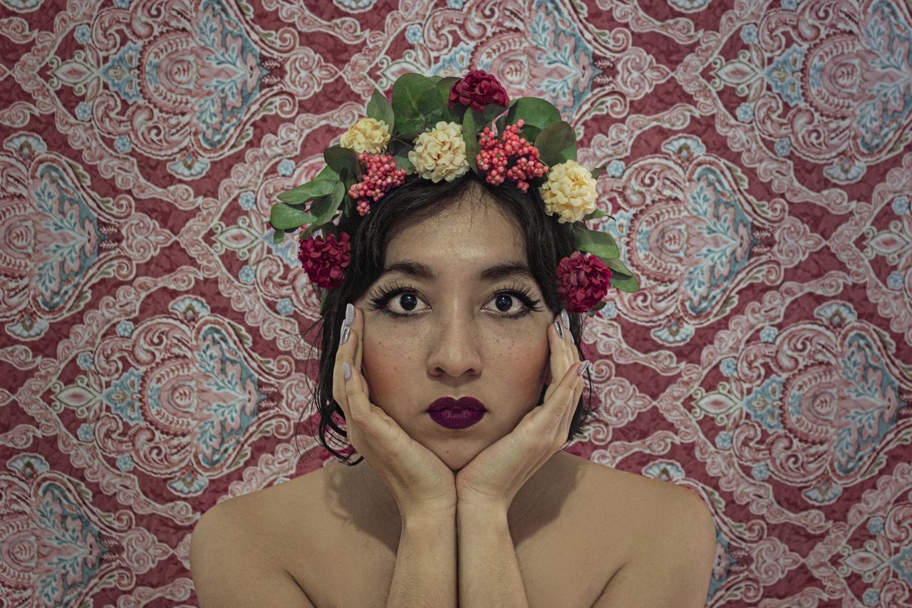 portrait, one person, women, adult, young adult, looking at camera, flower, headshot, pattern, indoors, floral pattern, front view, flowering plant, wallpaper, fashion, female, fashion accessory, person, human face, hairstyle, lifestyles, bride, beauty in nature, clothing, red, plant, make-up, brown hair, studio shot, elegance, creativity, serious