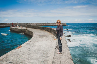 Full length of woman walking on retaining wall at pier