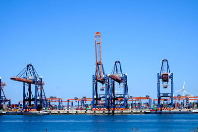 Cranes at commercial dock against clear sky