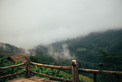 Road leading towards mountains against sky during foggy weather