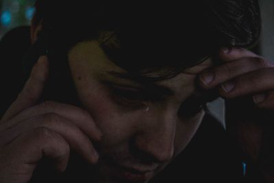 Close-up of young sad man talking on phone