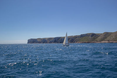 Sailboat on sea against clear blue sky