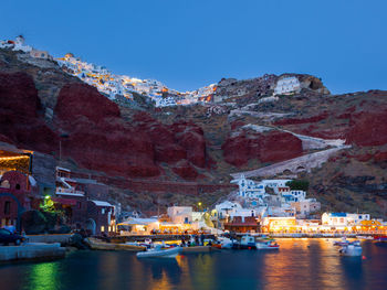 Boats in sea by buildings in town against sky