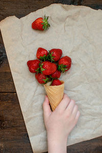 High angle view of hand with strawberries