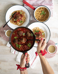 Cropped hands of woman serving spaghetti with meatballs on table