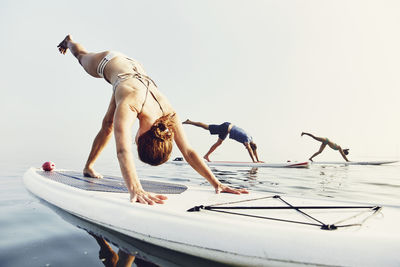 A group of standup paddle boarders doing yoga at sunrise in the fog