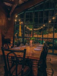 Empty chairs and tables in illuminated restaurant at night