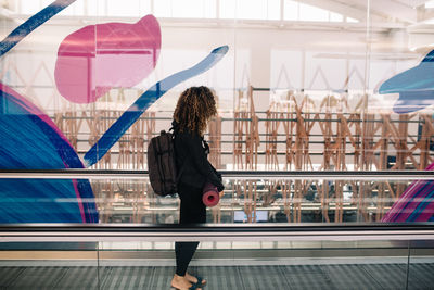 Rear view of woman standing against railing