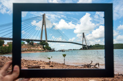 View of suspension bridge against cloudy sky