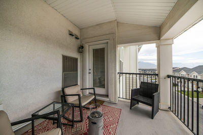 Empty chairs and tables in balcony against building